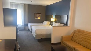 Een hotelkamer met twee bedden, een sofa, een tafeltje en een televisie.