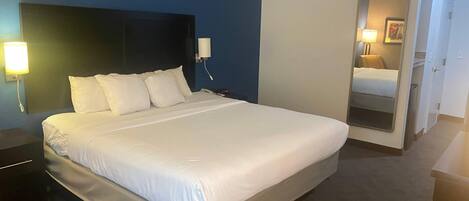 A hotel room with a large bed, bedside lamps, a bedside phone, and a mirror on the wall.