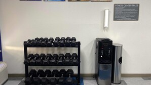 Een fitnessruimte met gewichten, een watervulstation en motiverende posters aan de muur.