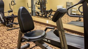 Een fitnessruimte met een hometrainer, een rekbank en diverse fitnessapparaten.