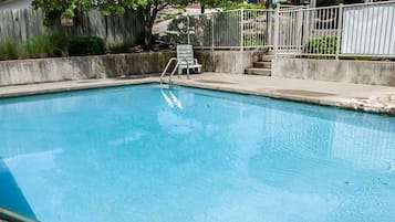 A clear swimming pool with a metal ladder and a single empty chair.