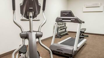 An indoor gym with an elliptical trainer, a treadmill, and a rack of dumbbells.