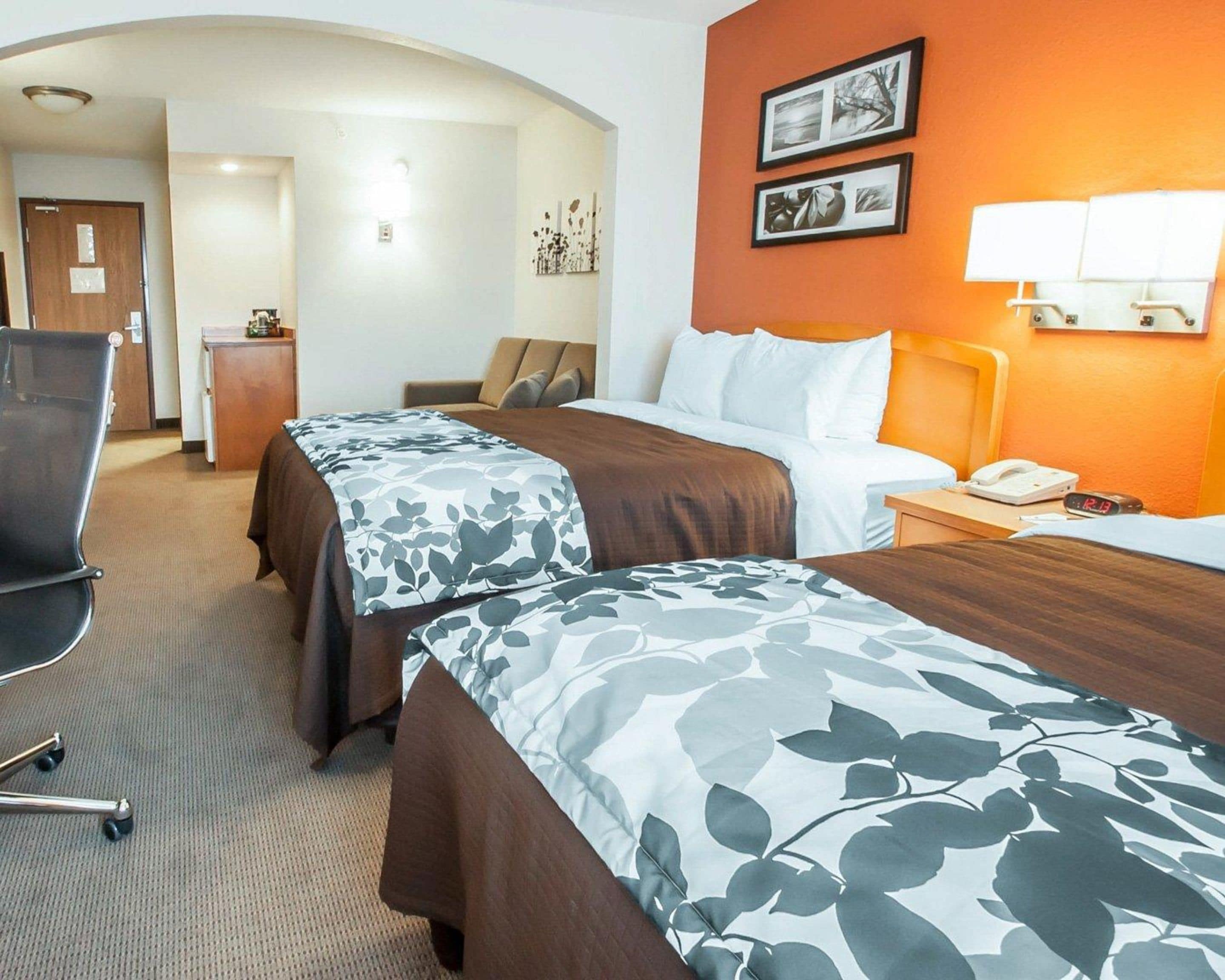 Habitación de hotel con dos camas, un escritorio, una silla y una lámpara.
