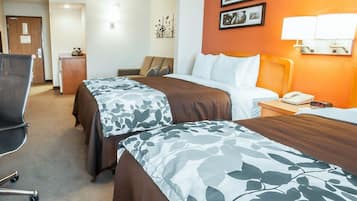 Habitación de hotel con dos camas, un escritorio, una silla y una lámpara.