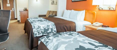 A hotel room with two beds, a desk, a chair, and a lamp.