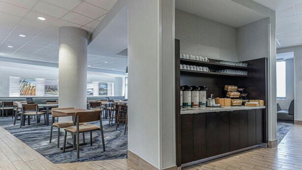 A modern hotel lobby with a seating area, a coffee station, and a view of the cityscape. - Fairfield Inn & Suites by Marriott St. John's Newfoundland (St. John's)