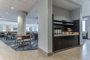 A modern hotel lobby with a seating area, a coffee station, and a view of the cityscape. - Fairfield Inn & Suites by Marriott St. John's Newfoundland (St. John's)