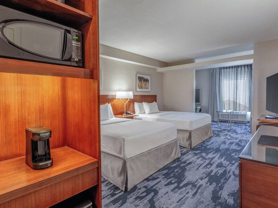 Habitación de hotel con dos camas, un escritorio, un microondas y un televisor.