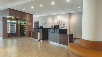 A hotel reception area with a corner market, a reception desk, and a seating area.