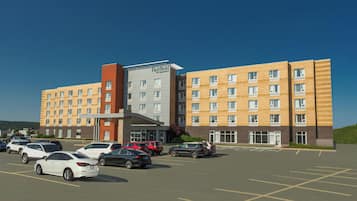 A multi-story hotel with a parking lot in front.