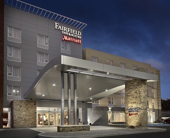 Un hôtel Fairfield Inn & Suites Marriott au design moderne, doté d’une entrée couverte et d’un pilier en pierre.