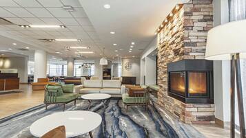 A spacious lobby with a stone fireplace, comfortable seating, and a modern ceiling design.