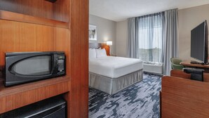 Habitación de hotel con cama, escritorio, computadora, microondas y televisión.