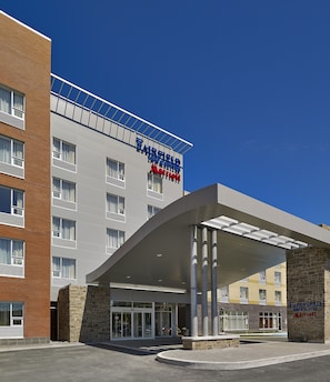 Un hôtel Fairfield Inn & Suites de la chaîne Marriott, doté d’un design moderne, avec une entrée imposante et un ciel d’un bleu éclatant.