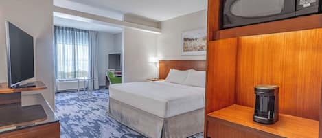 Una habitación de hotel con una cama, televisor, cafetera y microondas.