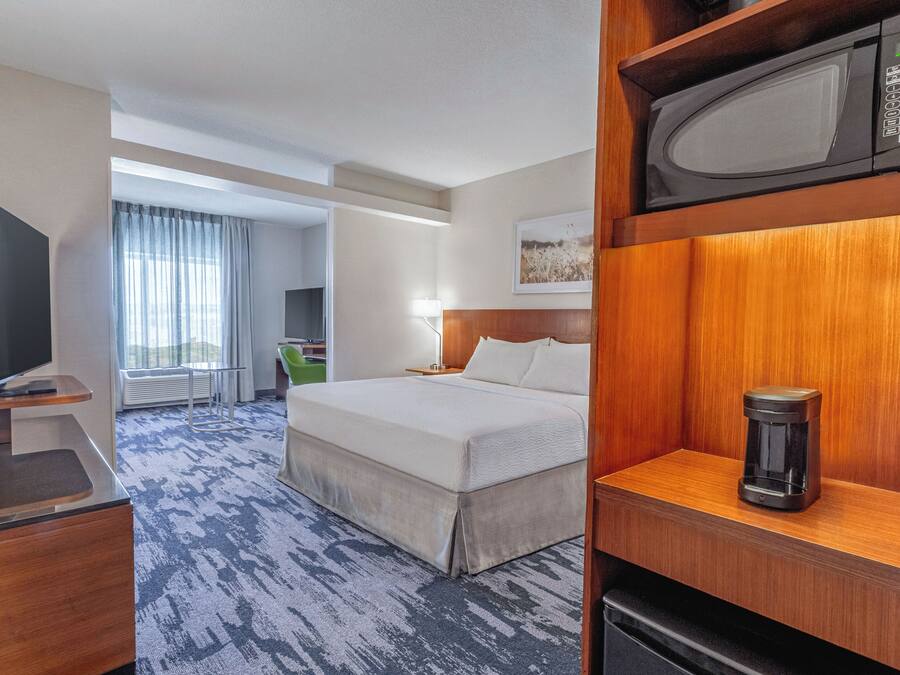 A hotel room with a bed, a television, a coffee maker, and a microwave.