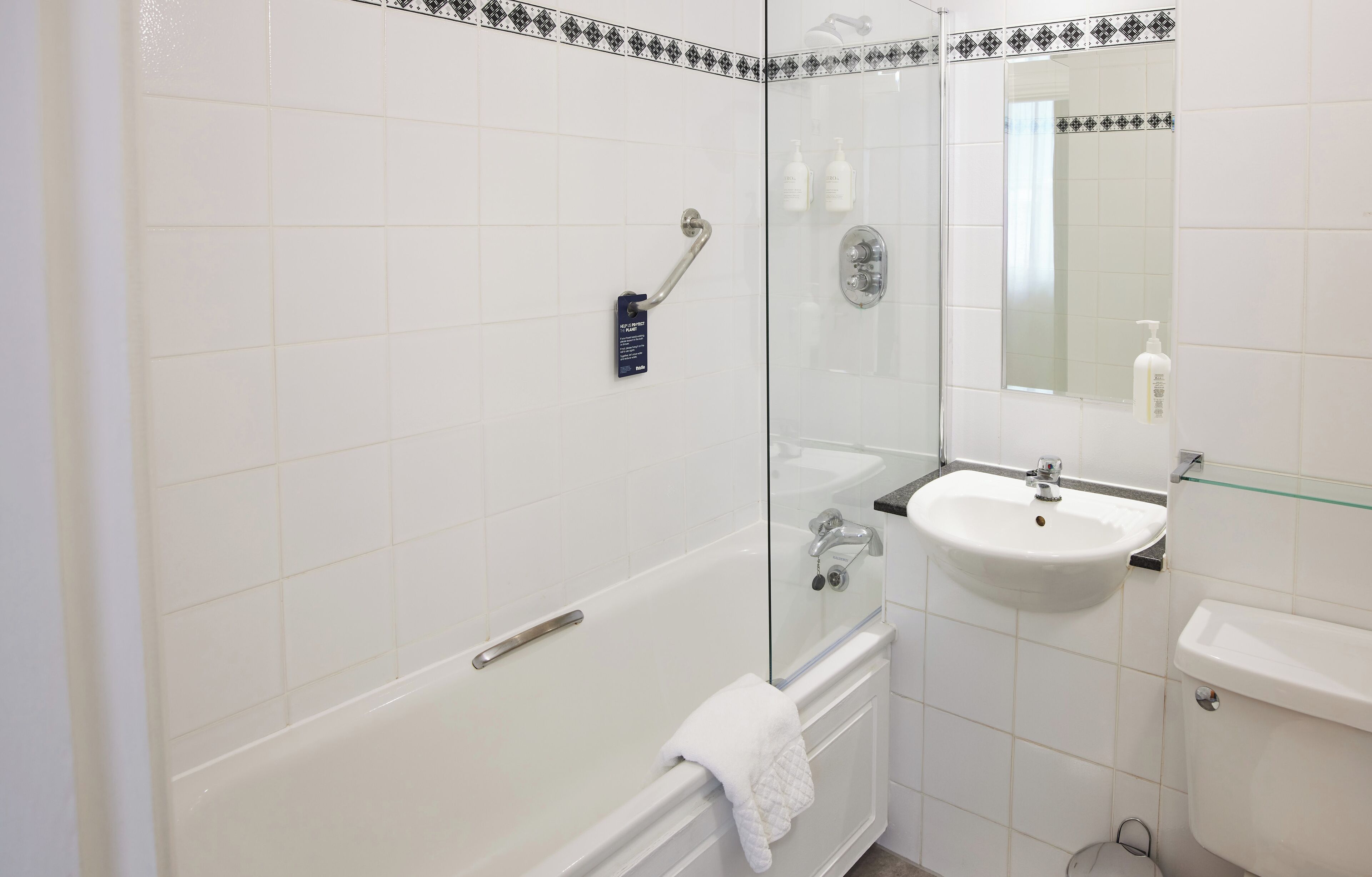 Un baño con ducha de vidrio, lavamanos blanco y un inodoro.