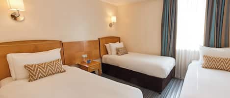 A hotel room with two beds, a nightstand, and a window with curtains.