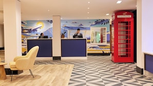Un área de recepción con mostrador de check-in, un teléfono rojo y un suelo estampado.