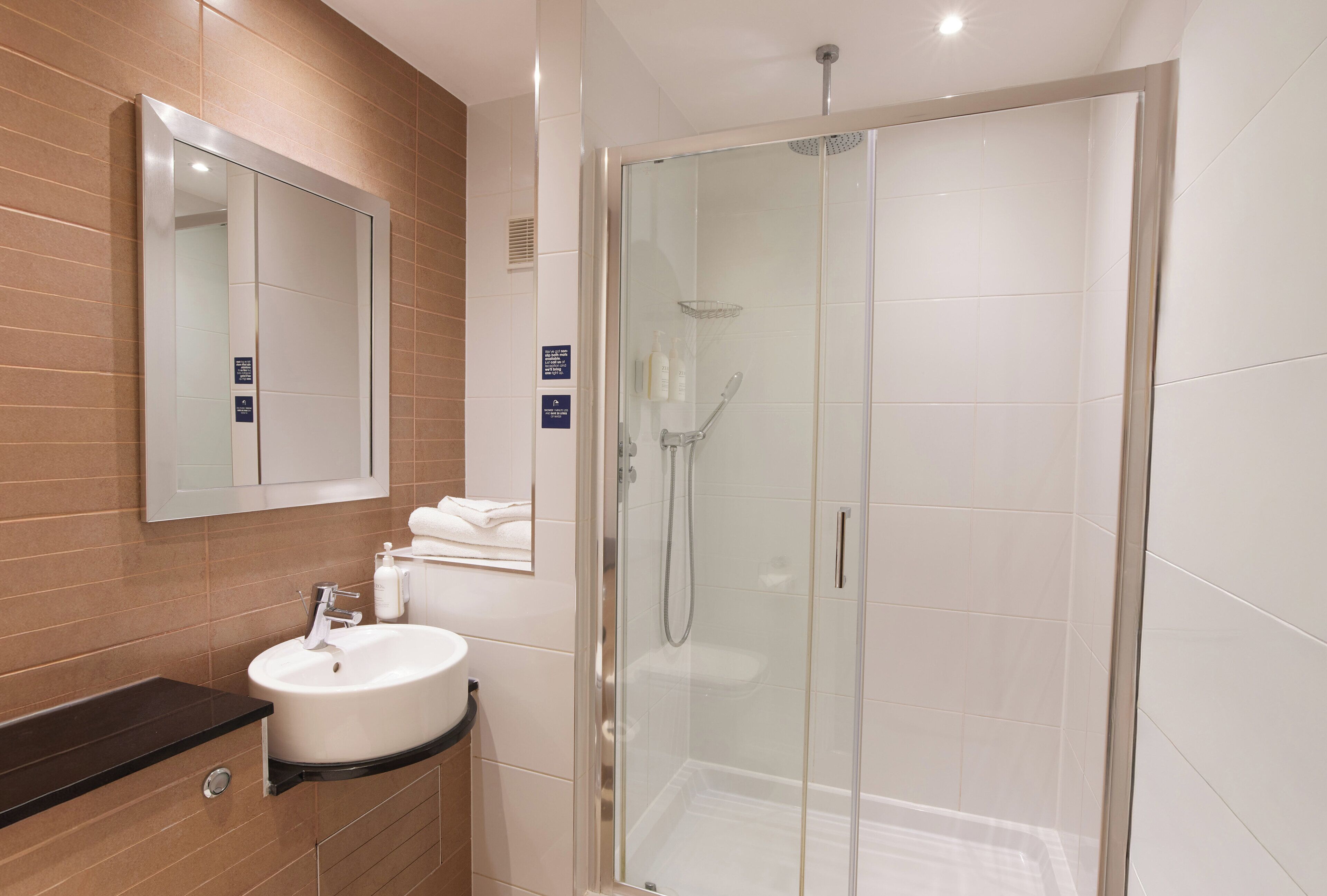 A modern bathroom with a glass-enclosed shower, a sink with a black countertop, and a mirror above the sink.