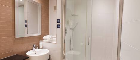 A modern bathroom with a glass-enclosed shower, a sink with a black countertop, and a mirror above the sink.