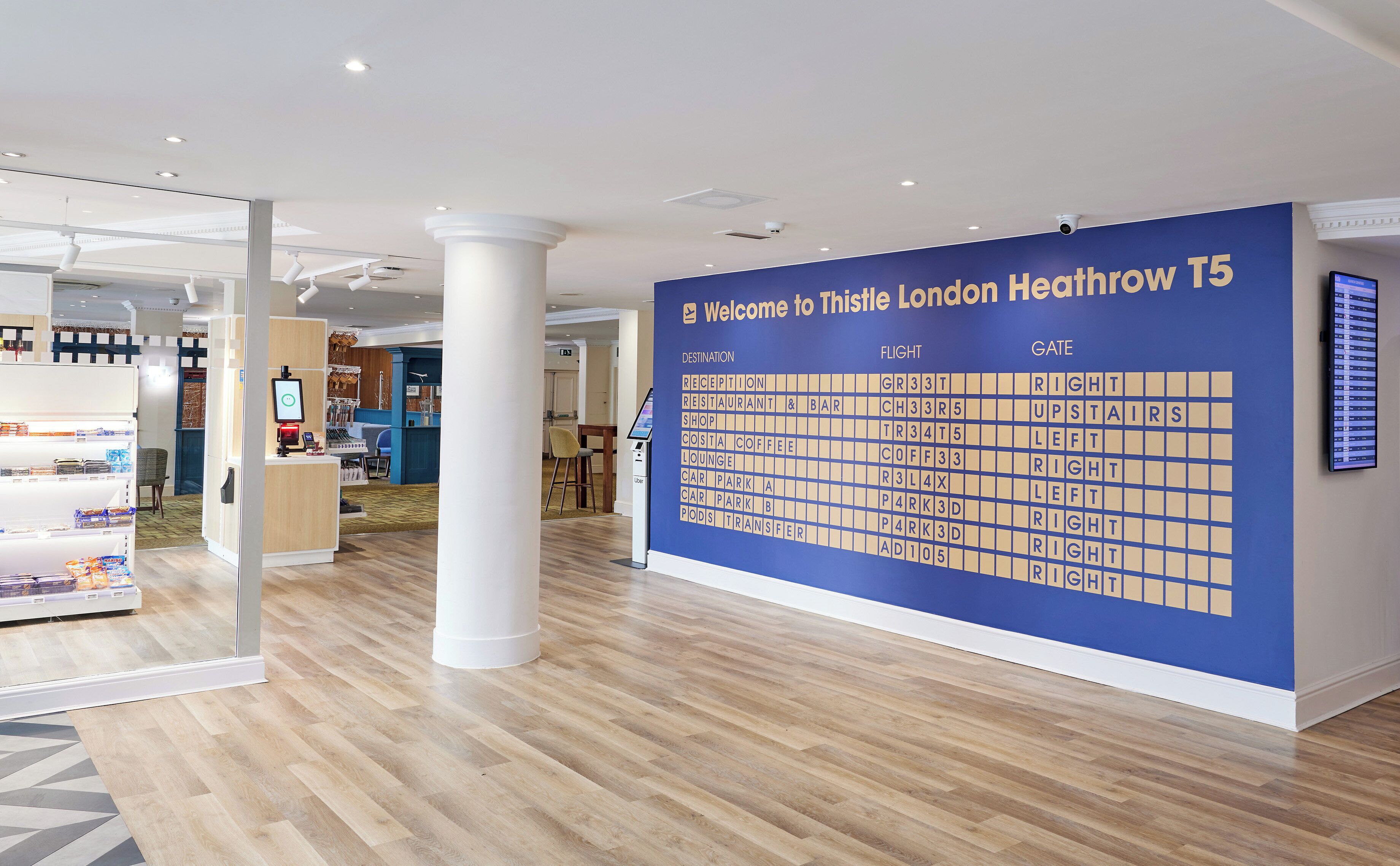 A reception area with a large information board, a reception desk, and a seating area with a coffee machine.