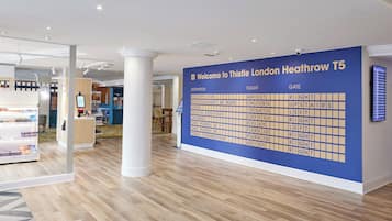 A reception area with a large information board, a reception desk, and a seating area with a coffee machine.