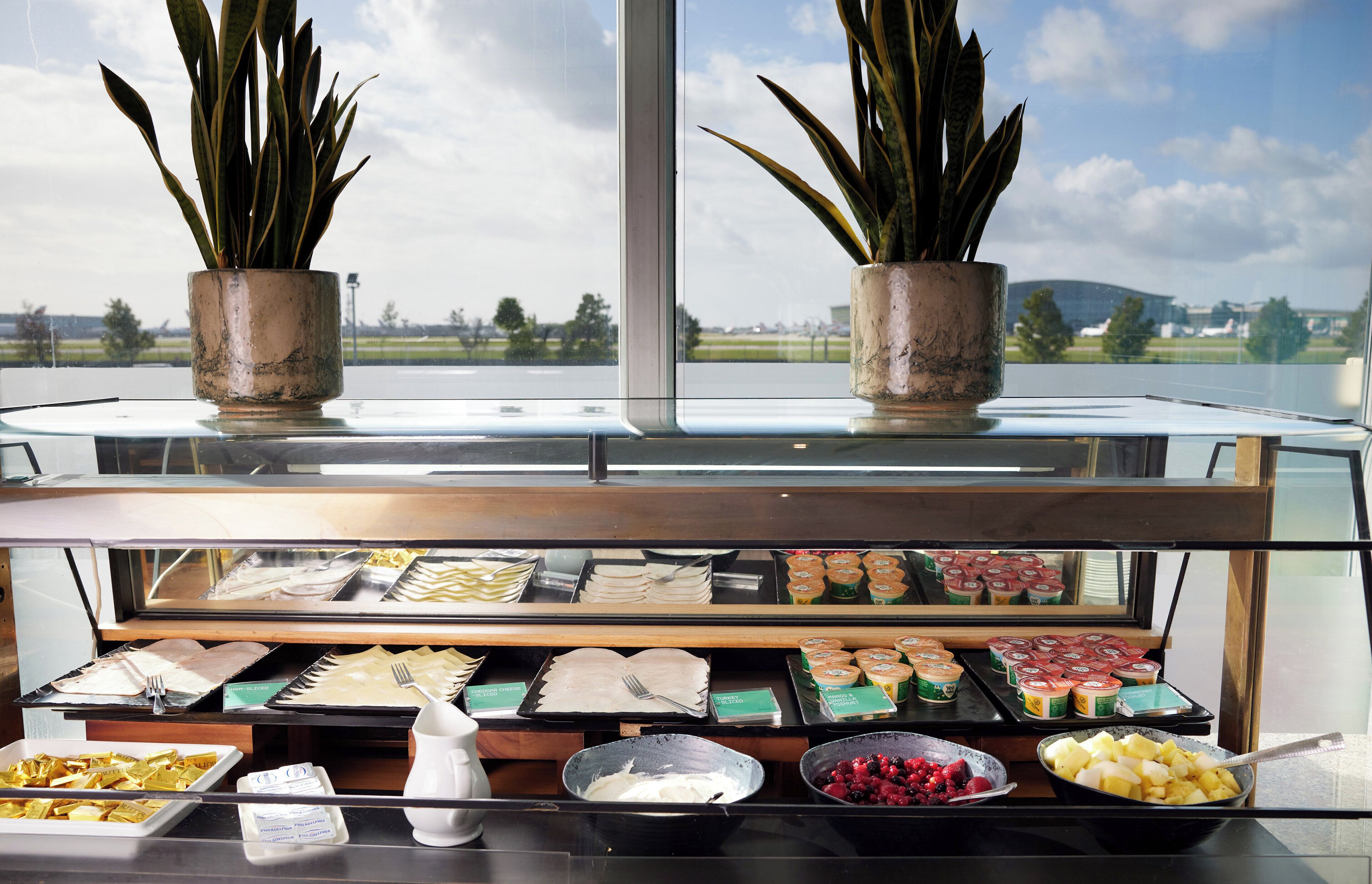 A buffet with various food items and a view of the outdoors through a window.