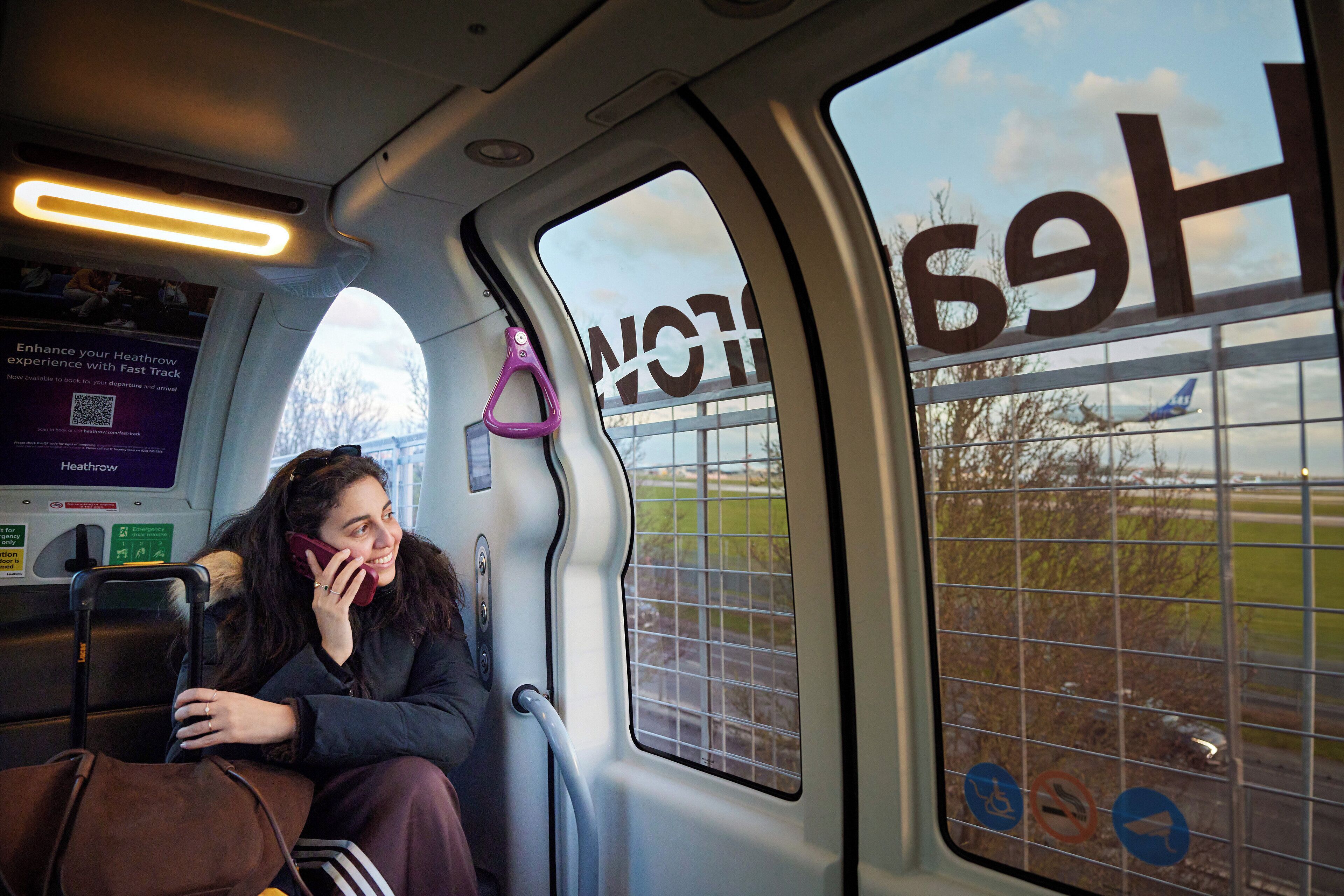 A person sitting inside a vehicle with a view of Heathrow Airport through the window.