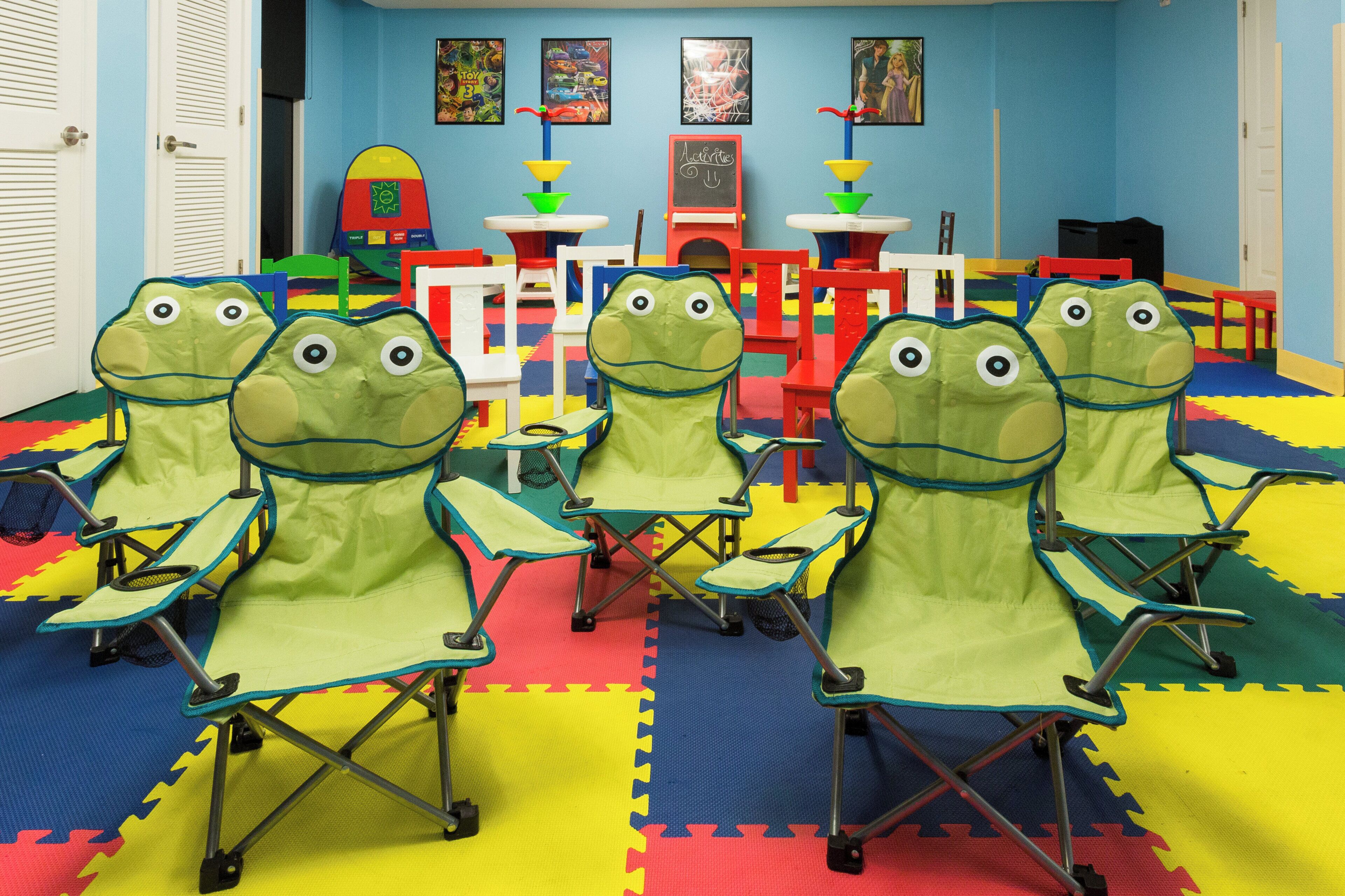 A room with colorful play mats, a red play table, and a white door.