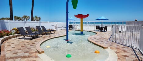 A pool area with a water feature, lounge chairs, and a view of the ocean.