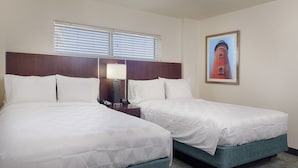 A hotel room with two beds, a nightstand with a lamp, a framed picture on the wall, and a window with blinds. - Holiday Inn Resort Daytona Beach Oceanfront by IHG (Daytona Beach)