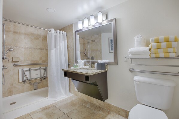 A bathroom with a shower, toilet, and a vanity with a mirror. - Holiday Inn Resort Daytona Beach Oceanfront by IHG (Daytona Beach)