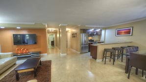A modern living room with a sofa, coffee table, and a TV mounted on the wall. There is a kitchen area with a refrigerator and microwave. - Holiday Inn Resort Daytona Beach Oceanfront by IHG (Daytona Beach)