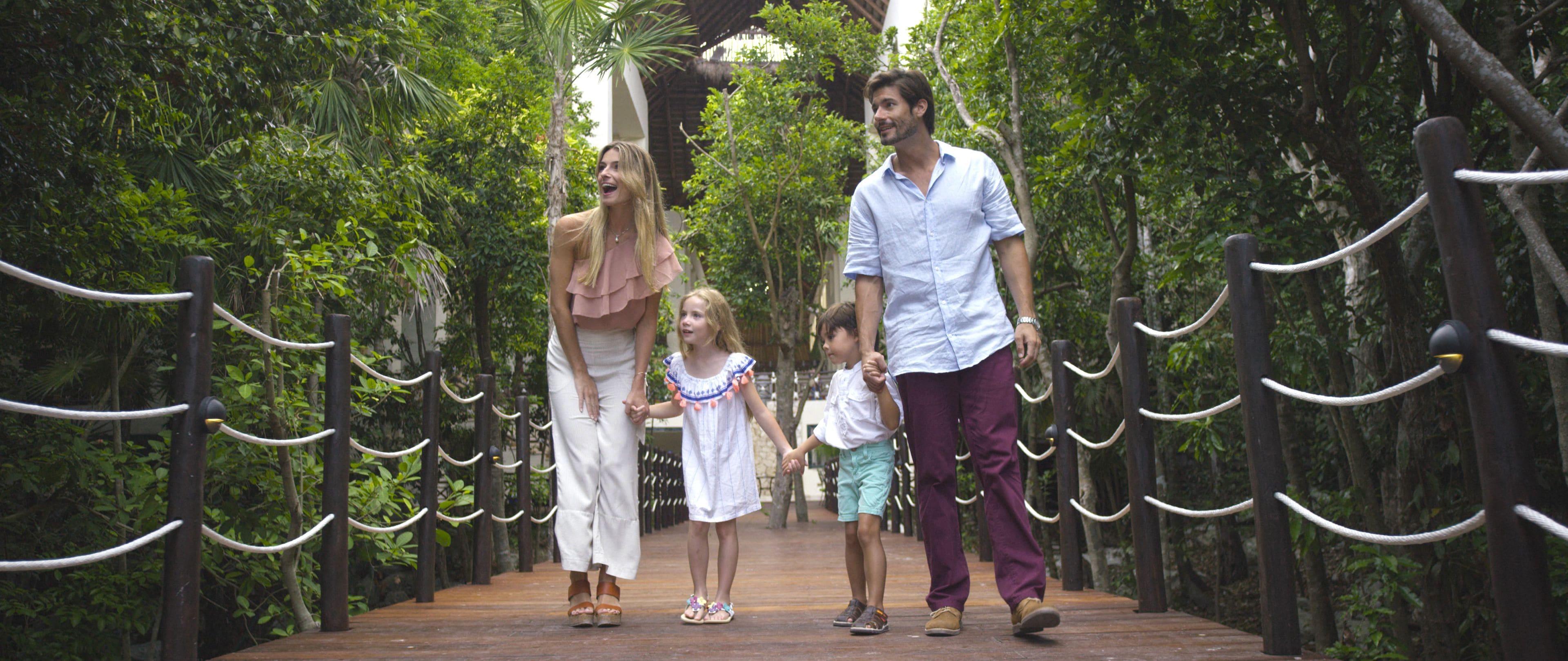 A wooden bridge with rope railings, surrounded by lush greenery.