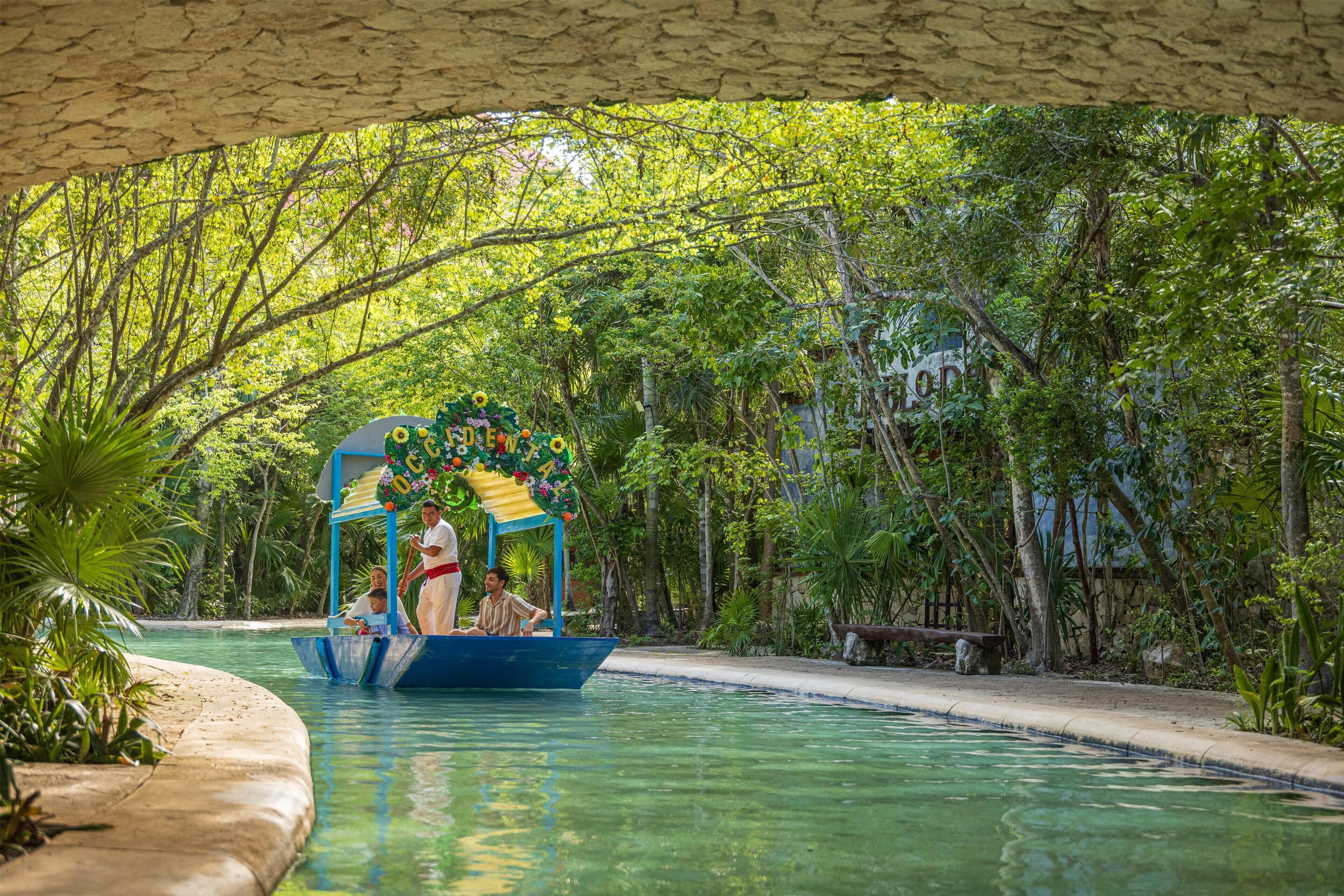 A boat ride on a clear pool with a canopy decorated with flowers, surrounded by lush greenery.