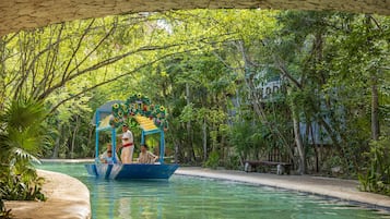 A boat ride on a clear pool with a canopy decorated with flowers, surrounded by lush greenery.