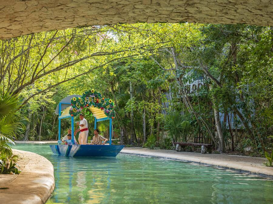 A boat ride on a clear pool with a canopy decorated with flowers, surrounded by lush greenery.