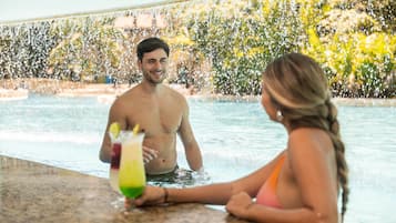 A man and a woman sitting by a pool with water splashing around them.