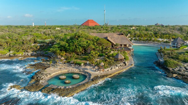 A resort with a pool, beachfront, and thatched-roof buildings.
