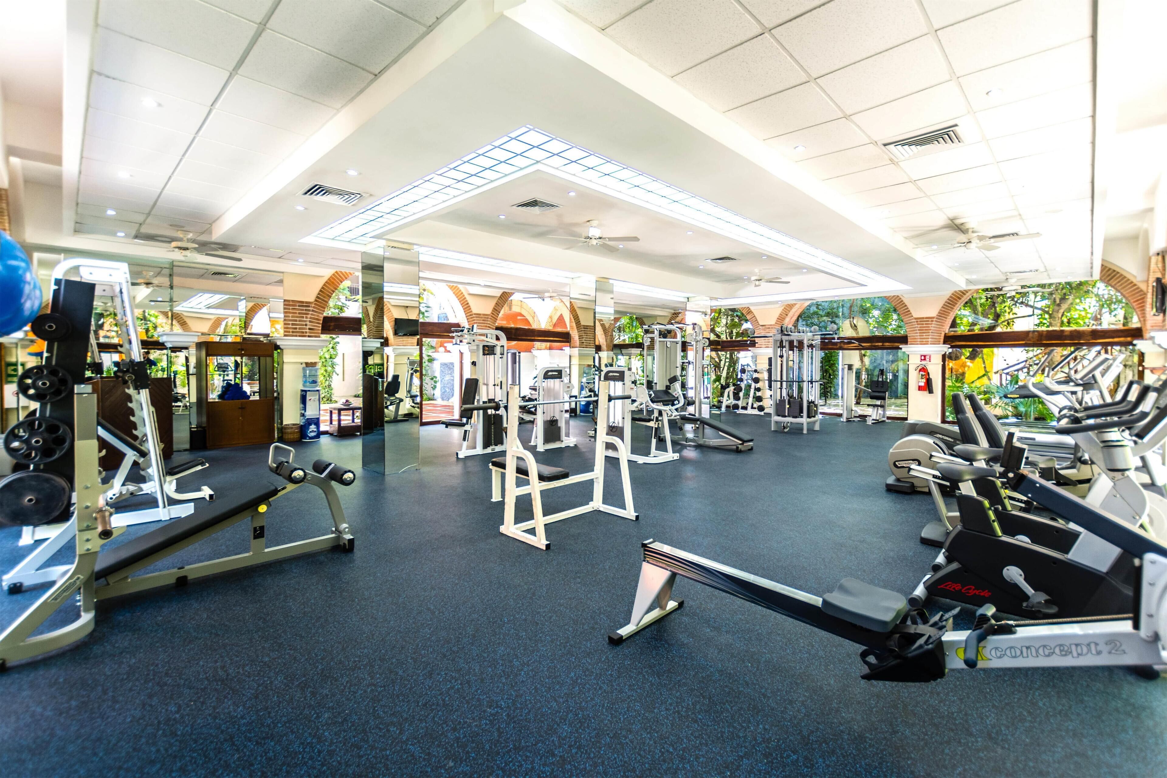 Ett gym med olika typer av träningsutrustning, inklusive löpband, styrketräningsmaskiner och fria vikter.