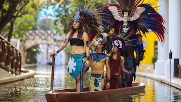 Un canal con una embarcación que transporta personas vestidas con trajes típicos.