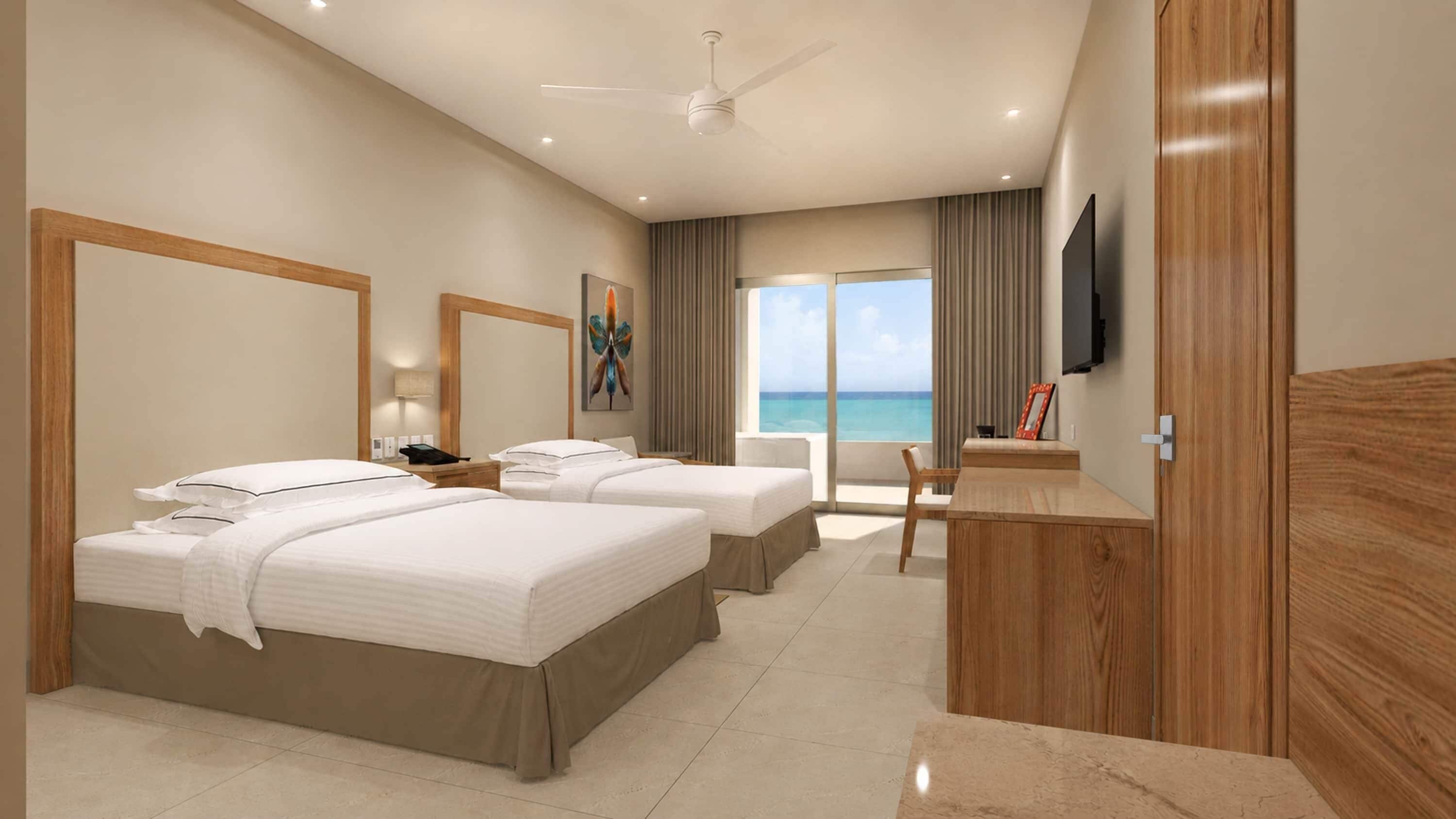 A hotel room with two beds, a desk, a chair, a TV, and a view of the ocean.