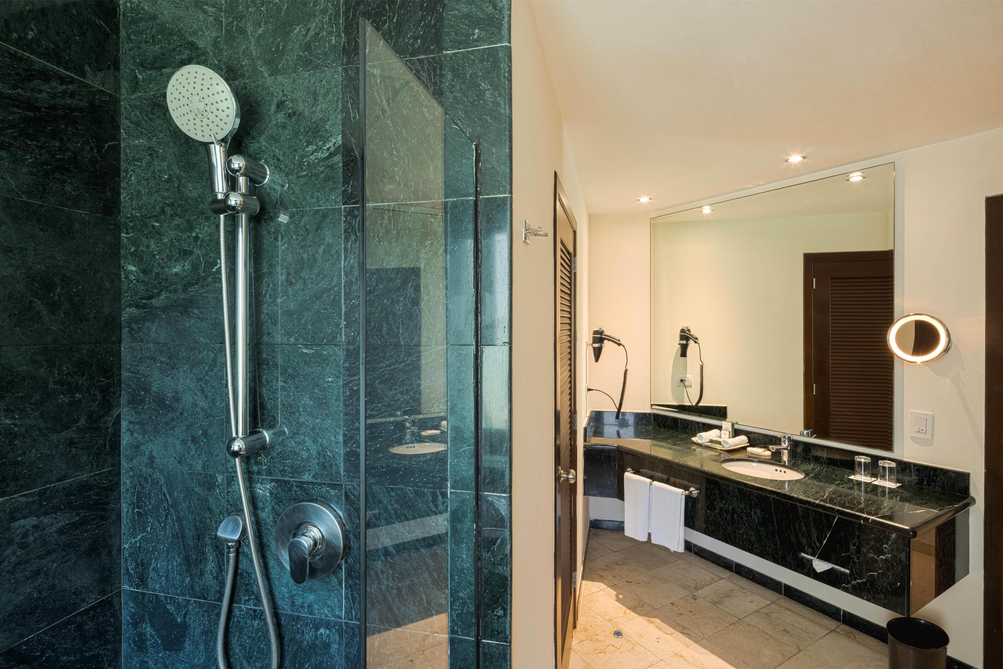 A modern bathroom with a glass-enclosed shower, a vanity with a mirror, and a sink.