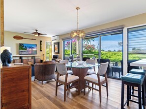 A spacious room with a large dining table, comfortable seating, a television, and a view of the outdoors.