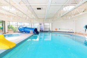An indoor swimming pool with a blue slide, a yellow slide, and a lifeguard stand. - Sandman Signature Vancouver Airport Hotel & Resort (Richmond)