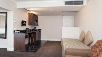 Una habitación de hotel compacta con kitchenette, una cama con ropa de cama a rayas y una pequeña zona de estar.