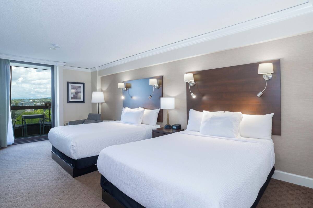 Une chambre d’hôtel avec deux lits, un balcon et une vue sur la ville.