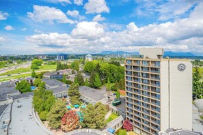 A high-rise hotel with multiple balconies, surrounded by greenery and other buildings. - Sandman Signature Vancouver Airport Hotel & Resort (Richmond)