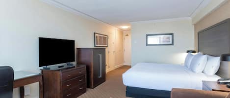 A hotel room with a bed, a desk with a TV, a dresser, and a chair.
